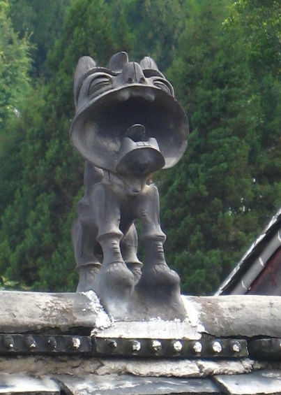 丽江古城老房子房顶的瓦脊上安放的一尊瓦猫,瓦猫怒目相对,驱鬼避邪