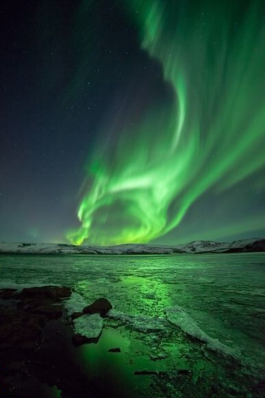 冰岛上空,鬼魅般的绿色北极光闪耀天际,照亮了这里冰冻的湖面.