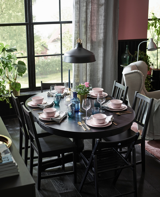 伸展型餐桌上摆放着浅粉色餐具和黄铜色刀叉,可供6个人坐下来享用晚餐