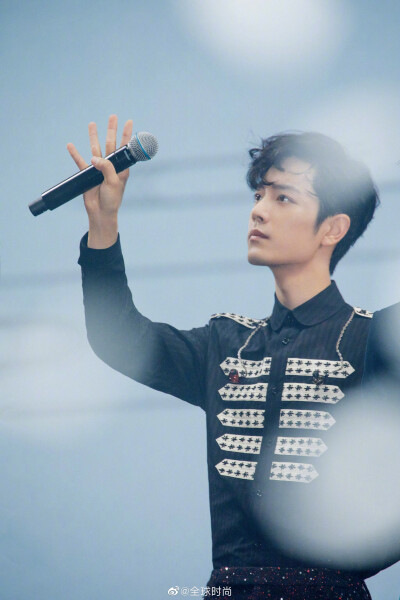 肖战以卷发发型搭配黑白色拼接西服及印花衬衫;王一博身着黑白色纹路